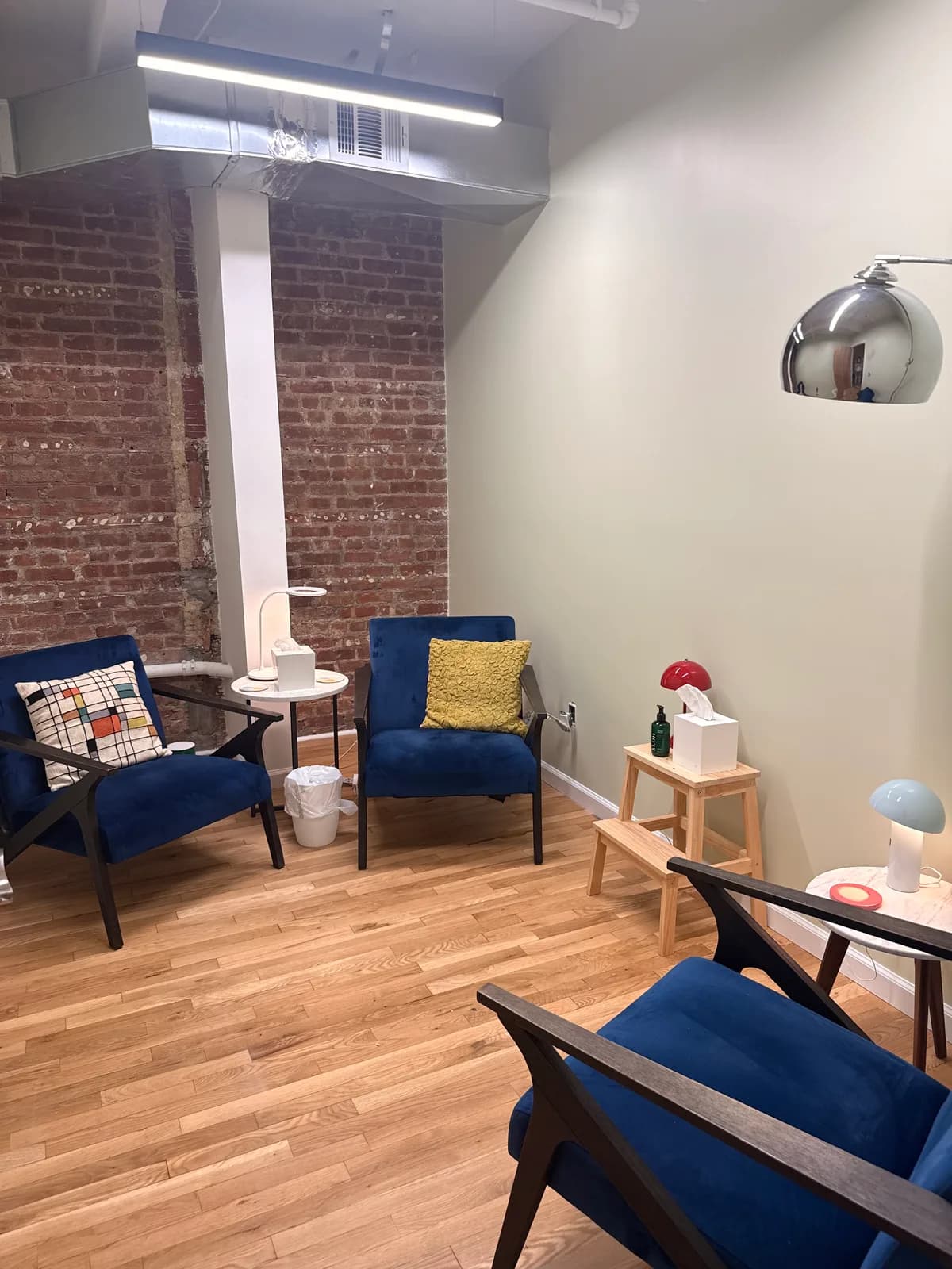 Consulting room with two blue velvet armchairs facing each other beside a brick column